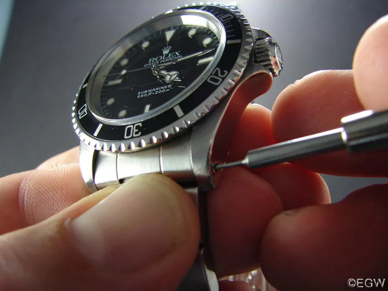 Federsteg-Werkzeug im Loch des Horns einer Rolex Submariner, gehalten zwischen den Fingern