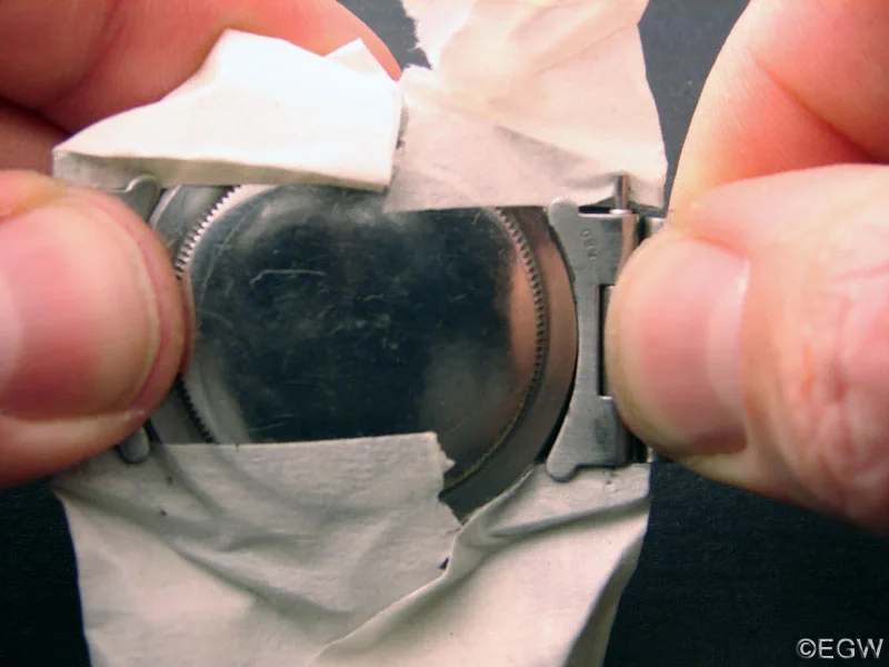 Finger drücken das Band zwischen die abgeklebten Hörner am Gehäuseboden