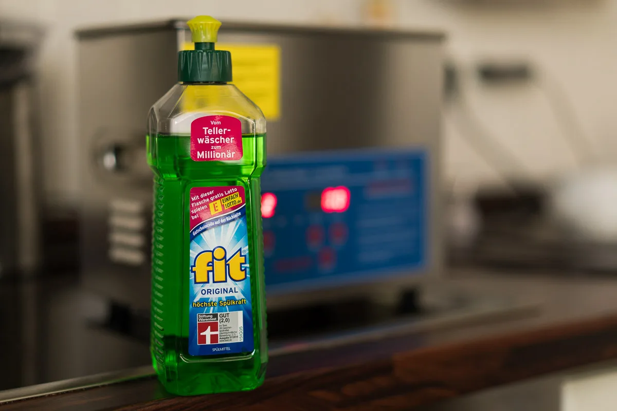 Bottle of dish soap in front of an ultrasonic cleaner