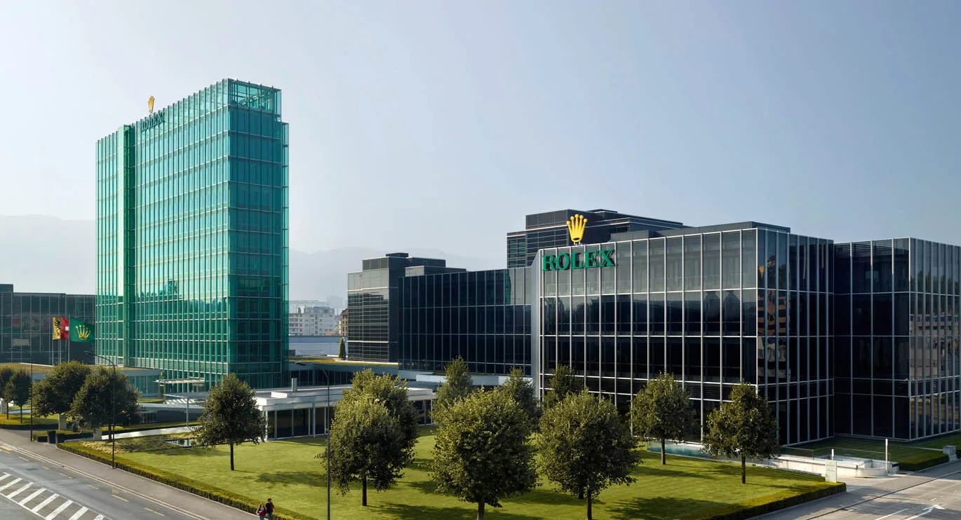 Rolex building in Geneva with a glass facade, with lawn and trees in front