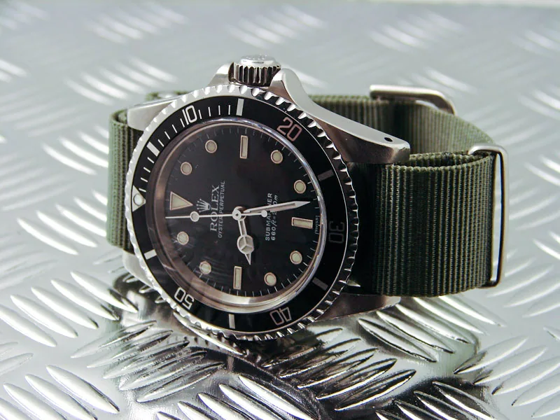 Rolex Submariner mit olivgrünem Natoband auf einer Riffelblech-Platte