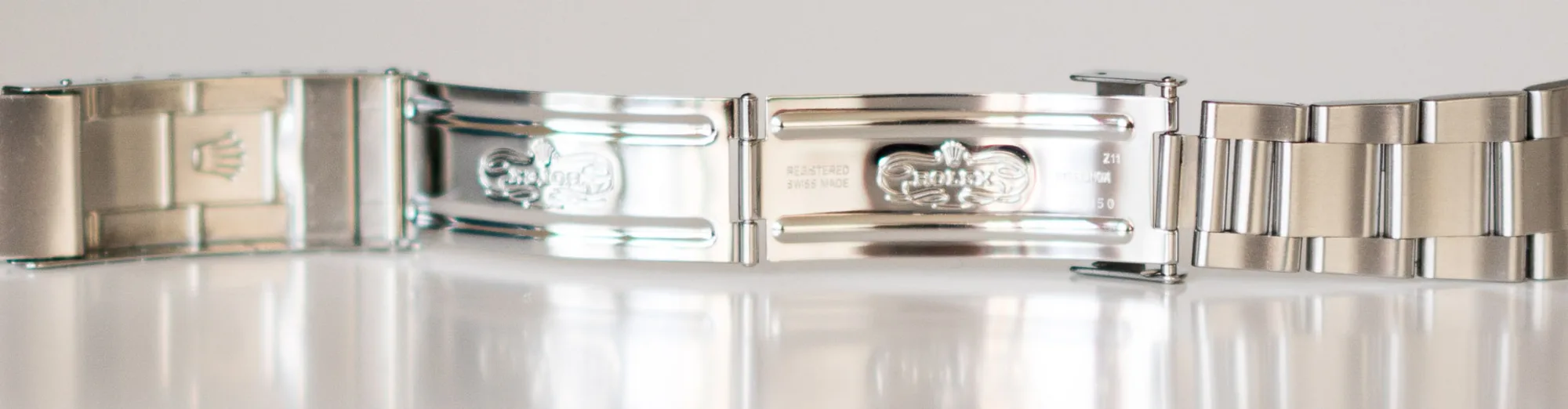Open Rolex clasp with the crown on a glossy surface