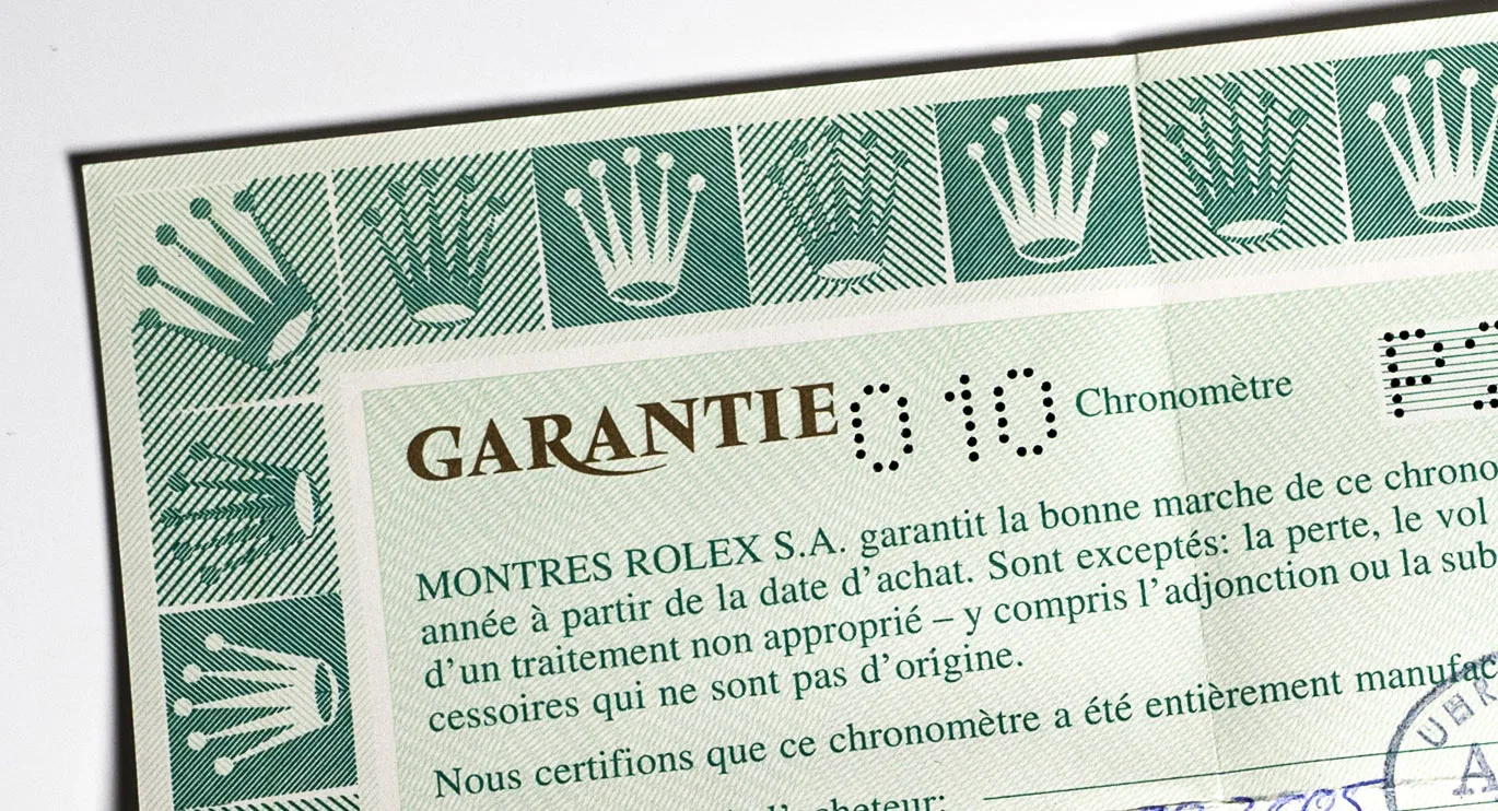 Detail of a Rolex warranty card with a green crown pattern and the customer code 010
