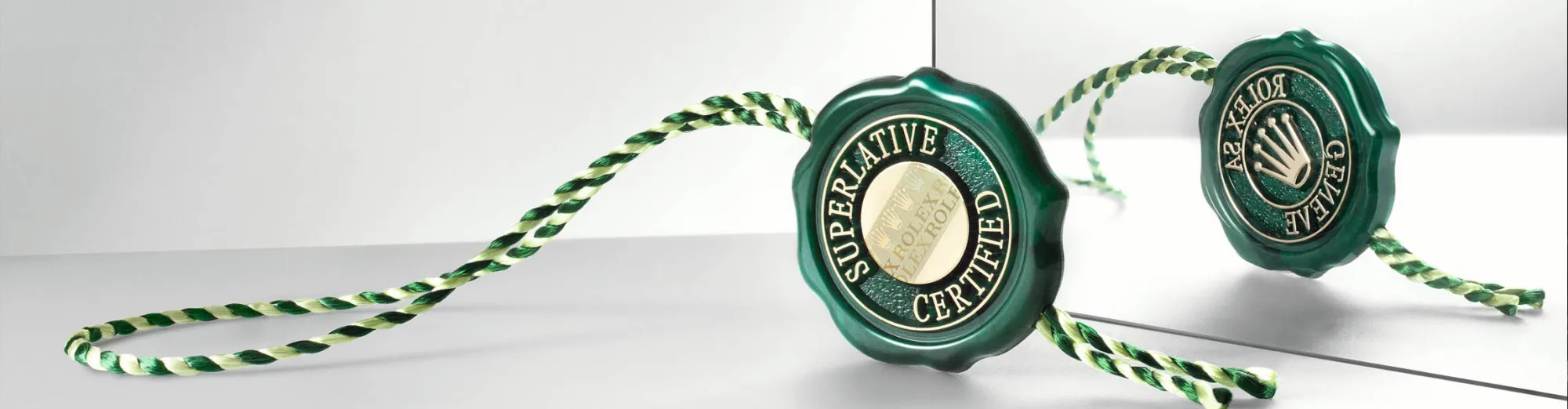 Zwei grüne Rolex Siegel mit der Aufschrift Superlative Chronometer Officially Certified an grün-weißer Kordel