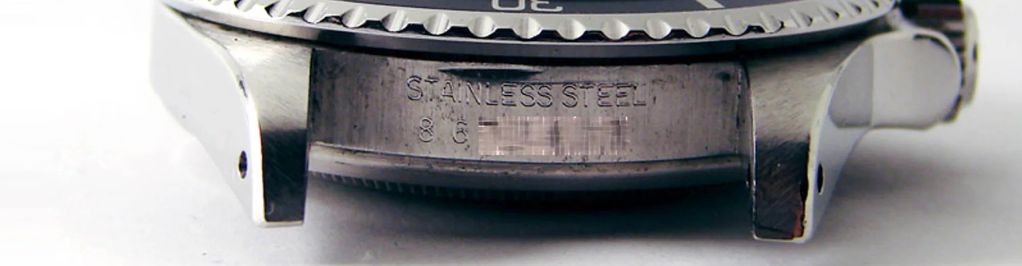 Case flank of a Rolex engraved STAINLESS STEEL, with a partly blurred-out serial number